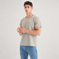 Silver-grey AJ512 round-neck T-shirt worn with blue jeans, with the model standing and hands together.